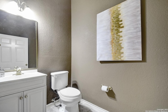 67 Oakwell Farms, San Antonio, TX 78218 - bathroom featuring toilet, vanity, baseboards, and a textured wall