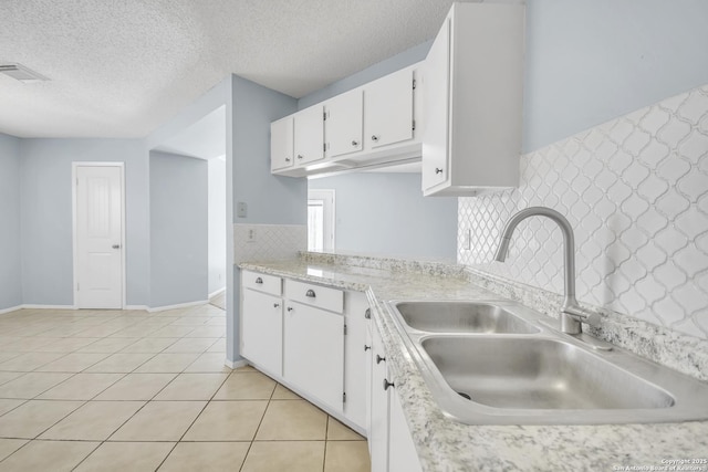 11202 Candle Park, San Antonio, TX 78249 - kitchen featuring a sink, light countertops, white cabinetry, light tile patterned floors, and a textured ceiling