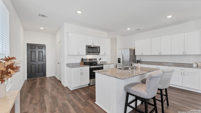 729 Heartseed Ave, New Braunfels, TX 78130 - kitchen featuring appliances with stainless steel finishes, dark wood-style flooring, white cabinetry, a kitchen island with sink, and a kitchen bar