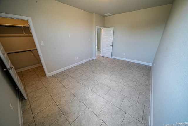 5721 Provo Pl, San Antonio, TX 78263 - unfurnished bedroom featuring a walk in closet, light tile patterned flooring, baseboards, and a closet