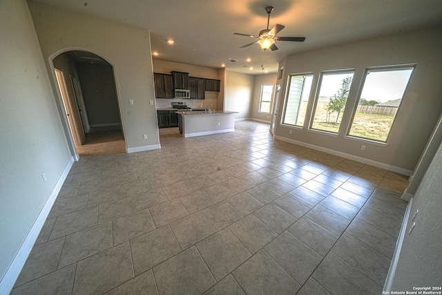 5721 Provo Pl, San Antonio, TX 78263 - unfurnished living room featuring arched walkways, ceiling fan, baseboards, light tile patterned flooring, and recessed lighting