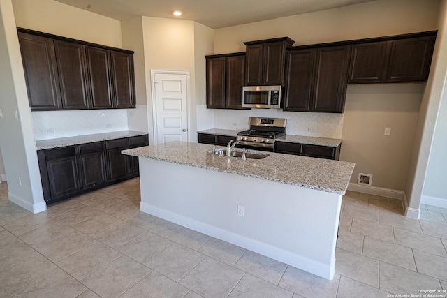 5721 Provo Pl, San Antonio, TX 78263 - kitchen with appliances with stainless steel finishes, a sink, backsplash, light stone counters, and a center island with sink
