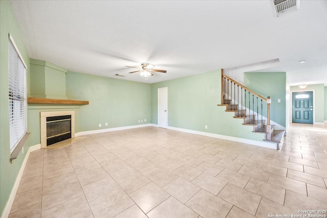 6119 Ferrysage, San Antonio, TX 78244 - unfurnished living room featuring ceiling fan, light tile patterned flooring, stairs, and a tiled fireplace