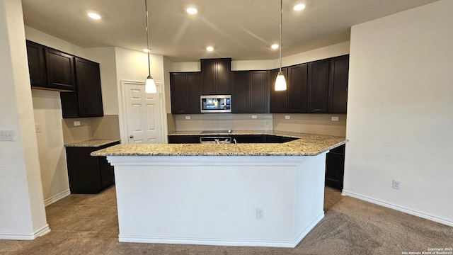 5930 Foster Bnd, San Antonio, TX 78244 - kitchen with stainless steel microwave, a center island with sink, backsplash, light stone counters, and recessed lighting