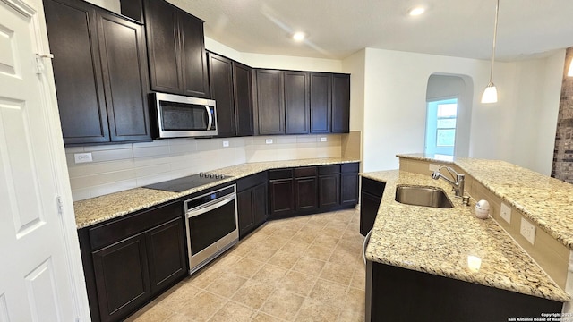 5930 Foster Bnd, San Antonio, TX 78244 - kitchen with appliances with stainless steel finishes, a sink, arched walkways, tasteful backsplash, and light stone countertops