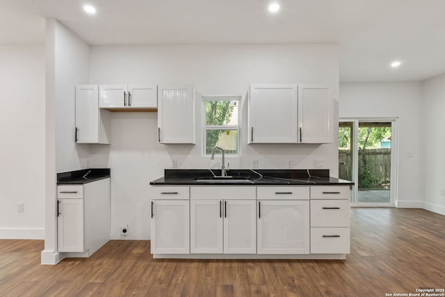 101 New York, San Antonio, TX 78214 - kitchen featuring a sink, wood finished floors, recessed lighting, dark countertops, and white cabinets