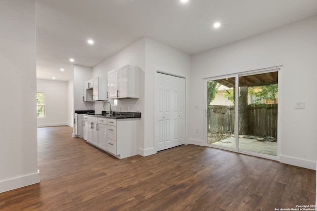 101 New York, San Antonio, TX 78214 - kitchen with dark countertops, a sink, dark wood-style flooring, white cabinets, and recessed lighting