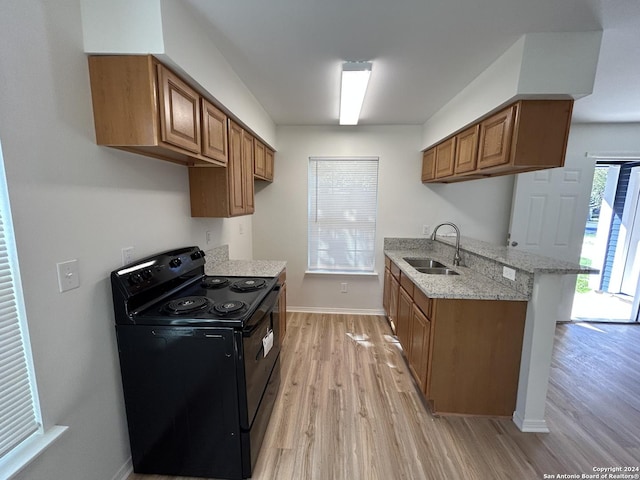 1807 Fresno, San Antonio, TX 78201 - kitchen featuring black range with electric stovetop, a sink, light wood-style floors, brown cabinets, and light stone countertops