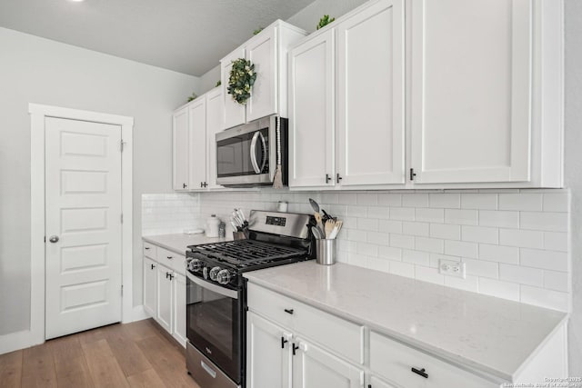 4538 Nueces, San Antonio, TX 78253 - kitchen with appliances with stainless steel finishes, light wood finished floors, white cabinets, backsplash, and light stone countertops