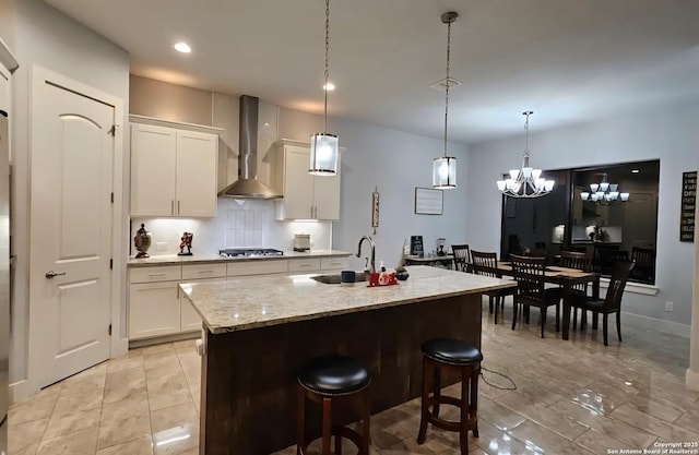 1726 Claudia Vis, San Antonio, TX 78224 - kitchen featuring wall chimney exhaust hood, a sink, light marble finish floors, decorative backsplash, and a kitchen island with sink