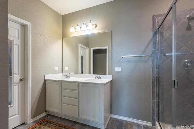 7566 Copper Kettle, Converse, TX 78109 - full bathroom featuring a textured wall, double vanity, a stall shower, baseboards, and wood finished floors