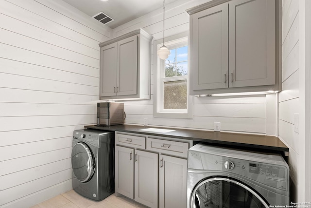 228 Cloverleaf, Alamo Heights, TX 78209 - laundry area with washer / dryer, cabinet space, light tile patterned floors, and wooden walls