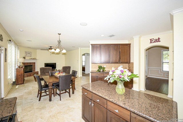 414 Aspen, San Antonio, TX 78253 - kitchen featuring arched walkways, ornamental molding, a brick fireplace, light stone countertops, and backsplash