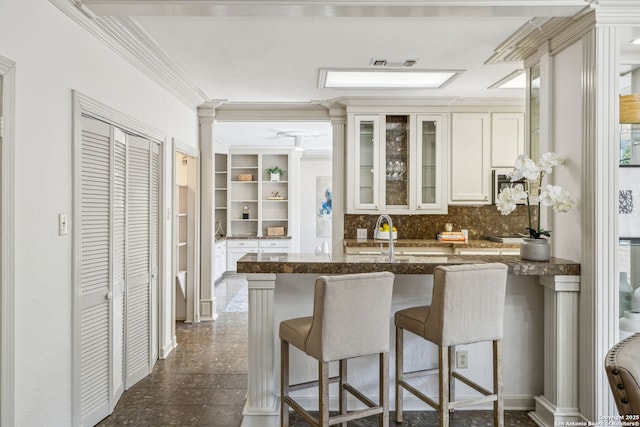 209 Chichester Pl Unit 1, San Antonio, TX 78209 - kitchen with crown molding, a sink, a kitchen breakfast bar, dark stone countertops, and tasteful backsplash