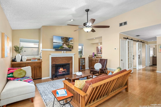 7738 Chambers Unit 612, San Antonio, TX 78229 - living room with vaulted ceiling, light wood finished floors, a barn door, a ceiling fan, and a premium fireplace