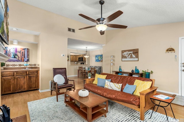 7738 Chambers Unit 612, San Antonio, TX 78229 - living room featuring ceiling fan, light wood-type flooring, baseboards, and a textured ceiling