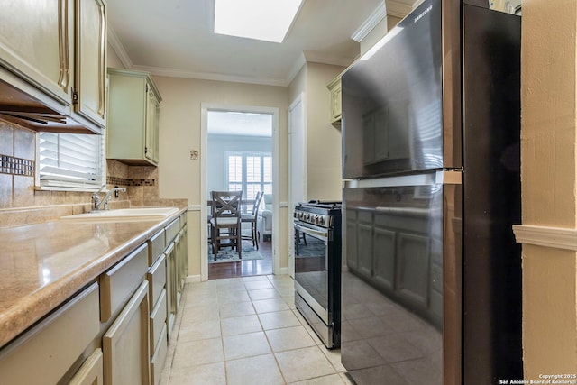 322 Pool, San Antonio, TX 78223 - kitchen with freestanding refrigerator, stainless steel gas stove, light tile patterned floors, light countertops, and crown molding