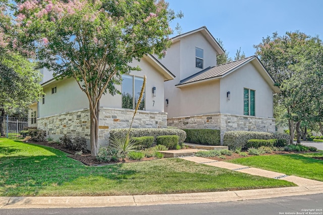 7 Saxby Gln, San Antonio, TX 78257 - view of front facade featuring a standing seam roof, stone siding, a front yard, and stucco siding