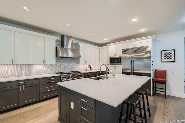 7 Saxby Gln, San Antonio, TX 78257 - kitchen with wall chimney exhaust hood, built in appliances, a sink, light wood-style floors, and white cabinetry