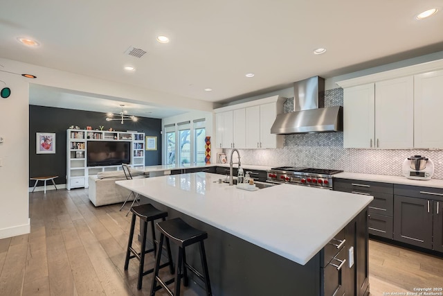 7 Saxby Gln, San Antonio, TX 78257 - kitchen featuring wall chimney range hood, a sink, high end range, light countertops, and tasteful backsplash