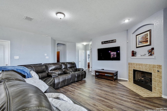 12535 Panola Way, San Antonio, TX 78253 - living area featuring wood finished floors, a tiled fireplace, a textured ceiling, and baseboards