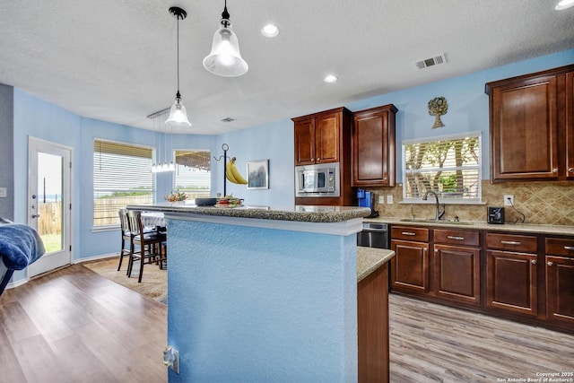 12535 Panola Way, San Antonio, TX 78253 - kitchen featuring a sink, light wood finished floors, appliances with stainless steel finishes, a center island, and tasteful backsplash