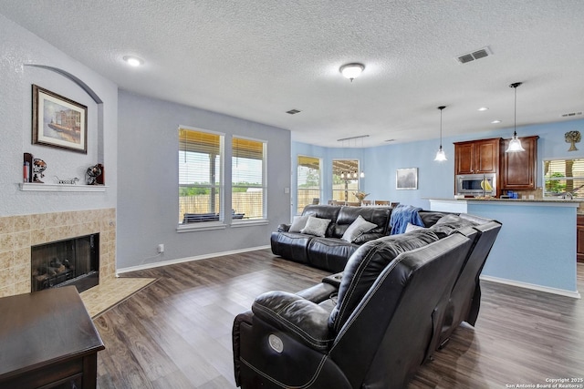 12535 Panola Way, San Antonio, TX 78253 - living area featuring dark wood-style floors, a tiled fireplace, a textured ceiling, baseboards, and recessed lighting