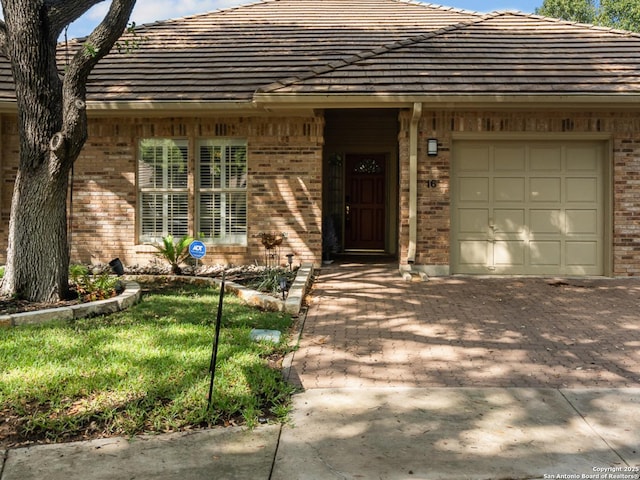 16 Cheshire, San Antonio, TX 78218 - property entrance with brick siding, a garage, and driveway