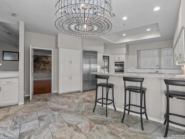 16 Cheshire, San Antonio, TX 78218 - kitchen featuring stainless steel appliances, light stone countertops, a peninsula, a kitchen breakfast bar, and white cabinetry