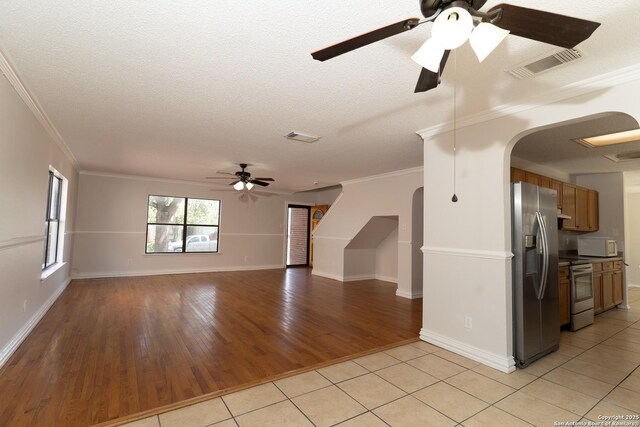 10322 Fork Crk, San Antonio, TX 78245 - unfurnished living room with ceiling fan, arched walkways, light tile patterned floors, ornamental molding, and baseboards