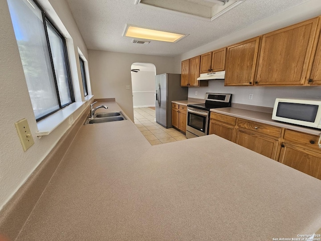 10322 Fork Crk, San Antonio, TX 78245 - kitchen featuring stainless steel appliances, a sink, arched walkways, under cabinet range hood, and a textured ceiling