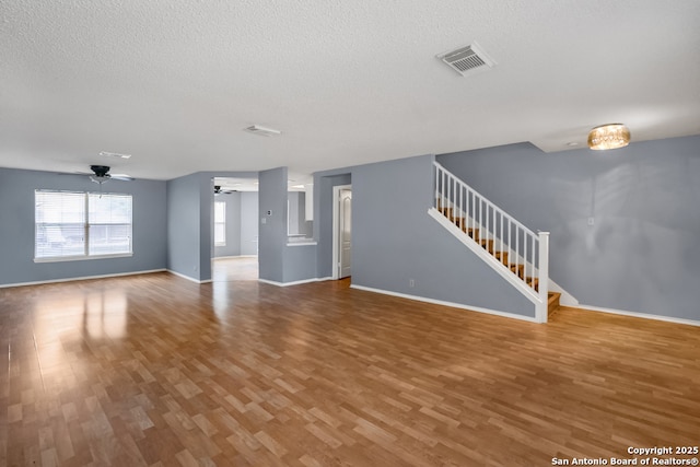 9503 Marshall Pt, San Antonio, TX 78240 - unfurnished living room featuring a ceiling fan, stairs, wood finished floors, a textured ceiling, and baseboards