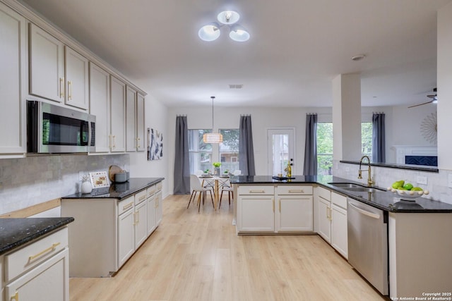 12031 Wellstone, San Antonio, TX 78249 - kitchen with appliances with stainless steel finishes, light wood-type flooring, a sink, decorative backsplash, and dark stone countertops