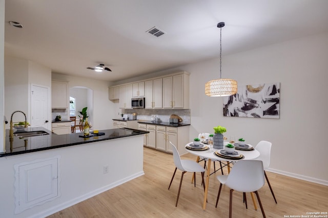 12031 Wellstone, San Antonio, TX 78249 - kitchen with a sink, stainless steel microwave, arched walkways, light wood finished floors, and tasteful backsplash
