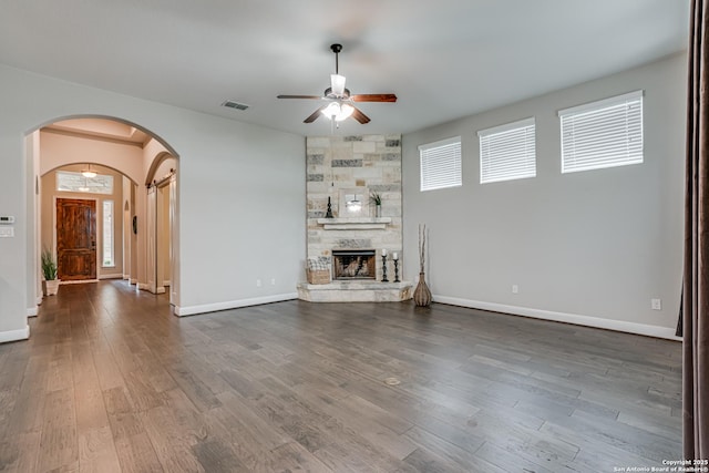 2714 Trailmont Dr, San Antonio, TX 78253 - unfurnished living room with a ceiling fan, arched walkways, dark wood finished floors, baseboards, and a stone fireplace