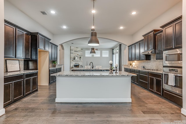2714 Trailmont Dr, San Antonio, TX 78253 - kitchen with appliances with stainless steel finishes, arched walkways, decorative backsplash, dark brown cabinetry, and recessed lighting