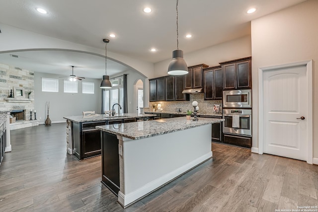 2714 Trailmont Dr, San Antonio, TX 78253 - kitchen with stainless steel appliances, arched walkways, a fireplace, ceiling fan, and open floor plan