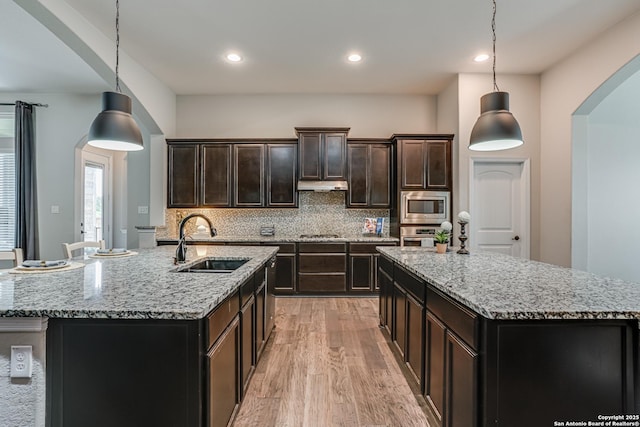 2714 Trailmont Dr, San Antonio, TX 78253 - kitchen with an island with sink, a sink, appliances with stainless steel finishes, under cabinet range hood, and light wood finished floors