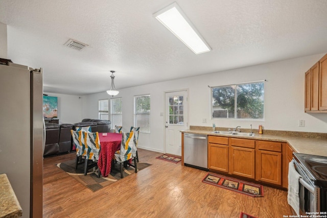 5815 Trent, San Antonio, TX 78249 - kitchen with appliances with stainless steel finishes, a sink, light wood-style floors, brown cabinets, and open floor plan