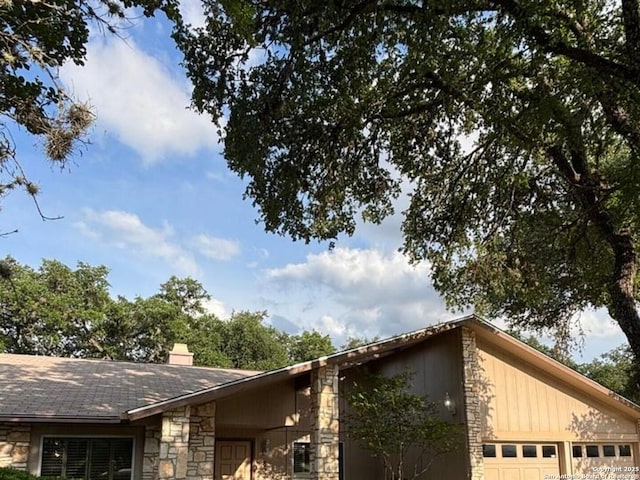 8526 Timberwilde, San Antonio, TX 78250 - view of side of property featuring stone siding, a chimney, and an attached garage