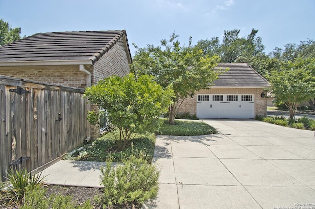 8 Kensington Ct, San Antonio, TX 78218 - view of side of home with brick siding, a tile roof, driveway, and an attached garage