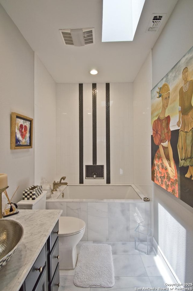 8 Kensington Ct, San Antonio, TX 78218 - bathroom with tiled tub, toilet, vanity, tile patterned flooring, and a skylight