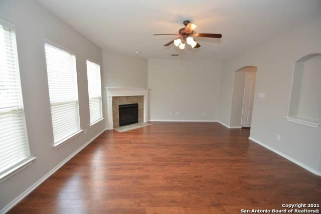 807 Maltese Gdn, San Antonio, TX 78260 - unfurnished living room featuring ceiling fan, arched walkways, a fireplace, and wood finished floors