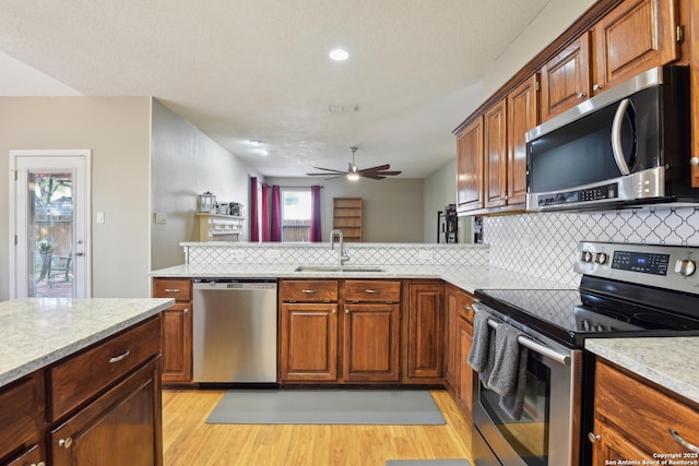 11823 Stanton, San Antonio, TX 78253 - kitchen featuring appliances with stainless steel finishes, a sink, ceiling fan, decorative backsplash, and light wood finished floors