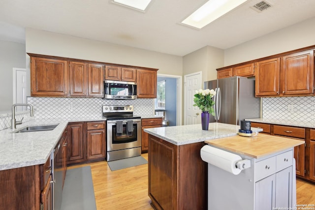 11823 Stanton, San Antonio, TX 78253 - kitchen with stainless steel appliances, a sink, light wood-type flooring, tasteful backsplash, and a center island
