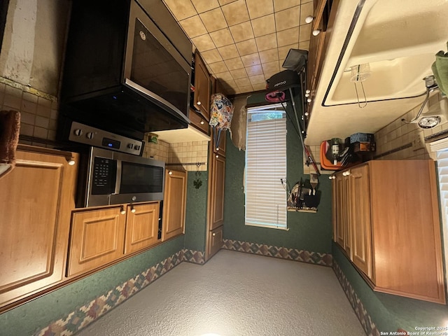 309 Royal, Converse, TX 78109 - kitchen with stainless steel microwave, baseboards, brown cabinetry, and carpet flooring