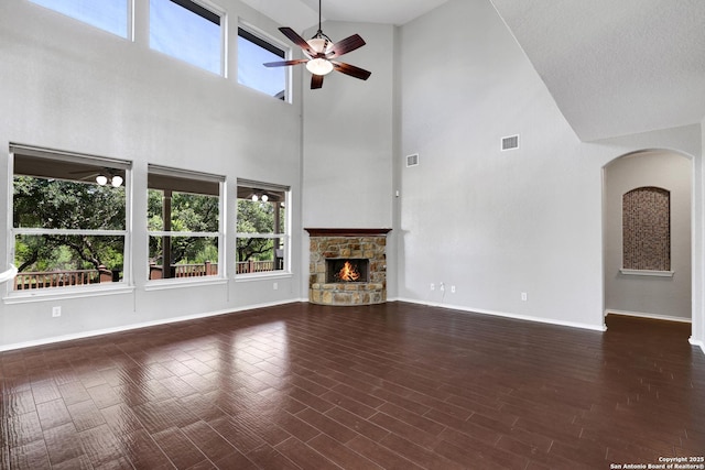 25511 Willard Path, San Antonio, TX 78261 - unfurnished living room featuring a high ceiling, ceiling fan, arched walkways, baseboards, and a stone fireplace
