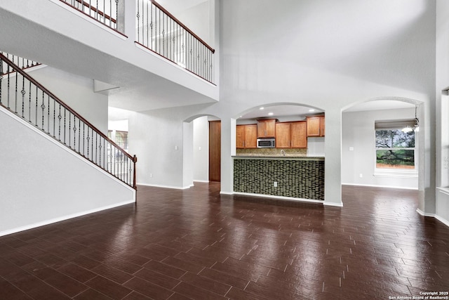 25511 Willard Path, San Antonio, TX 78261 - unfurnished living room featuring a high ceiling, baseboards, arched walkways, and stairs