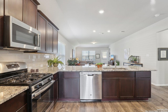 6131 Akin, San Antonio, TX 78261 - kitchen with appliances with stainless steel finishes, a sink, light wood-type flooring, a peninsula, and tasteful backsplash