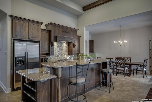 26358 Tawny Way, Boerne, TX 78015 - kitchen with appliances with stainless steel finishes, backsplash, a breakfast bar area, light stone counters, and dark brown cabinets